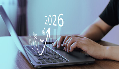 Close-up of hands working on laptop with futuristic financial graphs and projections for 2026,...