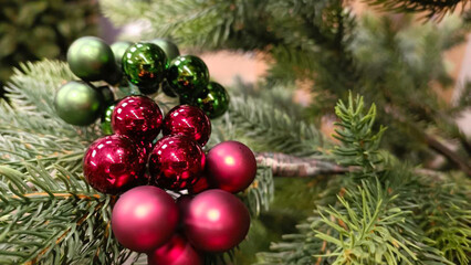 Decorated Christmas tree with red and green balls on blurred background.
