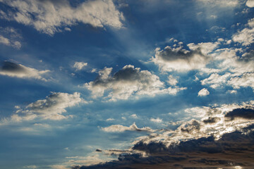 Deep blue sun rays casting over white cumulus clouds