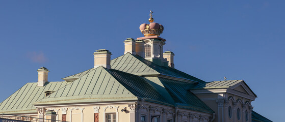 Close-up view of the roof and golden crown atop the Grand Menshikov Palace in Oranienbaum under a clear blue autumn sky.