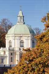 Dome and architectural details of the Grand Menshikov Palace in the Oranienbaum palace and park ensemble framed by autumn trees under a clear blue sky.