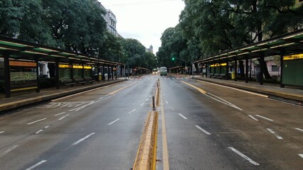 default
Wide shot of an empty street in downtown Buenos Aires, Argentina. The scene features tall buildings, including shops and residential units, lining both sides of the street. Prominent signs and