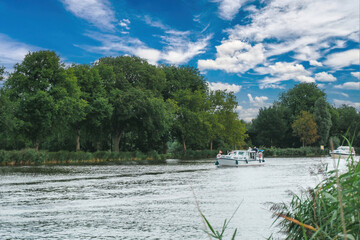 Boat traveling across a lake in Holland, with vegetation in the background.