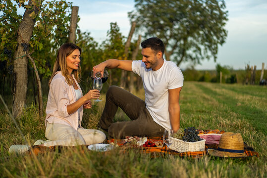 Couple enjoying a romantic picnic with wine in a vineyard setting