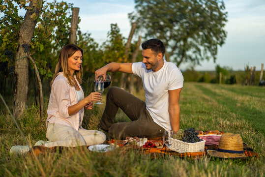 Couple enjoying a romantic picnic with wine in a vineyard setting - Powered by Adobe