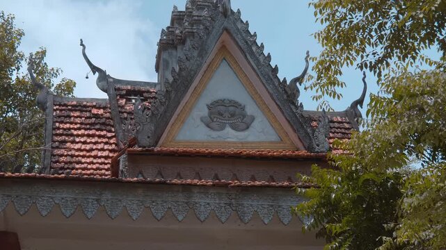 Golden chofas (traditional Asian serpent-like roof decorations) on the roof of Wat Svay Romeat Pagoda, Siem Reap, Cambodia. Shot in motion