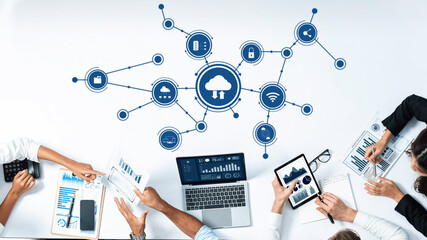 A modern workspace showcasing teamwork in cloud computing, featuring digital devices, data visualization, and collaboration around a sleek table for business analysis. Amity