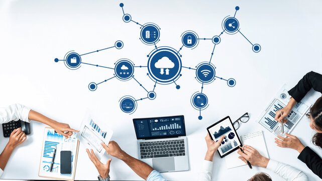 A modern workspace showcasing teamwork in cloud computing, featuring digital devices, data visualization, and collaboration around a sleek table for business analysis. Amity