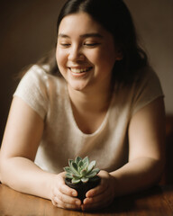 Smiling girl holds succulent plant in cozy indoor setting