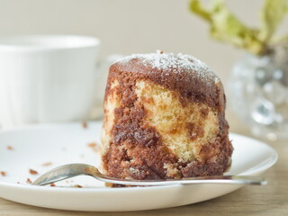 Slice of Marble Cake - A delicious slice of homemade marble cake with powdered sugar on a white plate with a spoon.