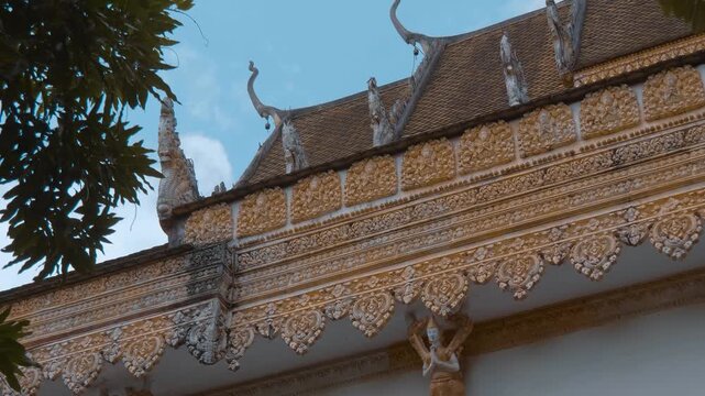 Golden chofas (serpent like roof decoration) on the tiled roof of Wat Kampong Phluk Buddhist temple are decorated with light garlands for celebration. Siem Reap, Cambodia. Shot in motion 