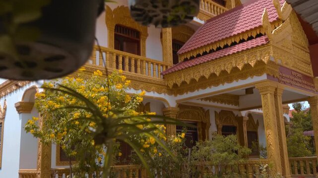 Beautiful Khmer Buddhist temple building with balconies and gold covered balusters and window frames intricately carved in Asian style. Siem Reap, Cambodia. Shot in motion