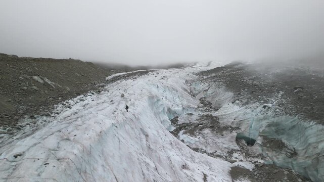 Eine winzig erscheinende Person l&auml;uft entlang einer Kante am Gletscher Mer de Glace in den franz&ouml;sischen Alpen nahe Chamonix.