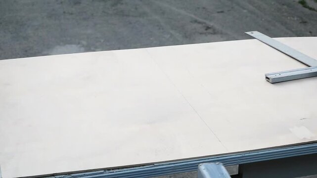 worker measures board for cutting