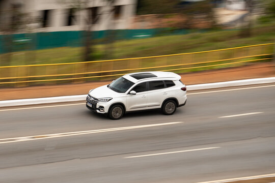 White Caoa Chery Tiggo 8 panning shot, 7-seater SUV driving on highway