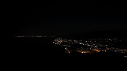 Aerial night view of illuminated coastal city skyline