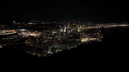 Aerial night view of illuminated coastal city skyline