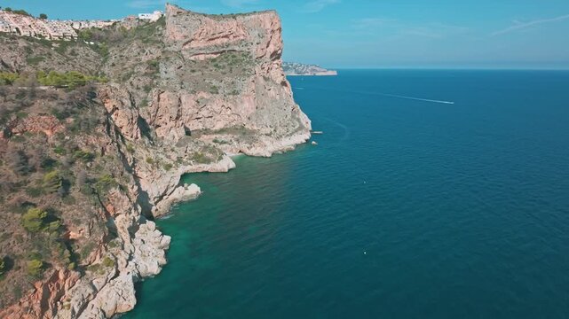 Aerial drone footage of Cala del Moraig cove and Mediterranean cliffs in Benitatxell, Spain. Clear blue water and rocky coastline on the Costa Blanca.