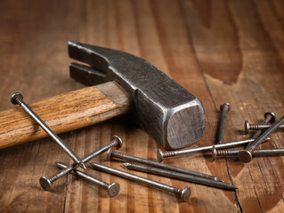 An old hammer and rusty nails resting on a wooden surface. Suitable for repair, construction, and craft-themed projects.