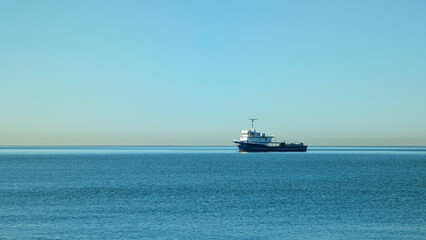 A blue and white fishing boat sails on a calm sea, with gentle waves.
