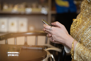 Elegant hand smartphone gold traditional dress jewelry ring bracelet cafe table graceful moment with elegant hand using smartphone cafe wearing gold traditional dress with ornate jewelry soft