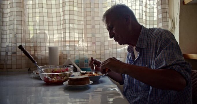 An elderly man enjoys a simple, healthy meal at home by himself. This video captures the quiet authenticity of his daily life and includes natural ambient sounds.
