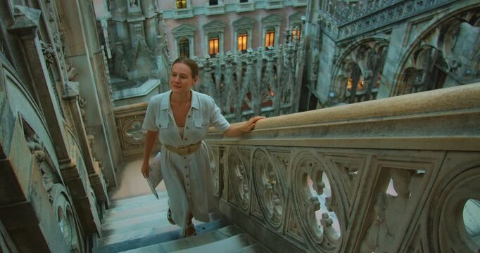 Woman climbing decorative stone stairs near intricate gothic architecture