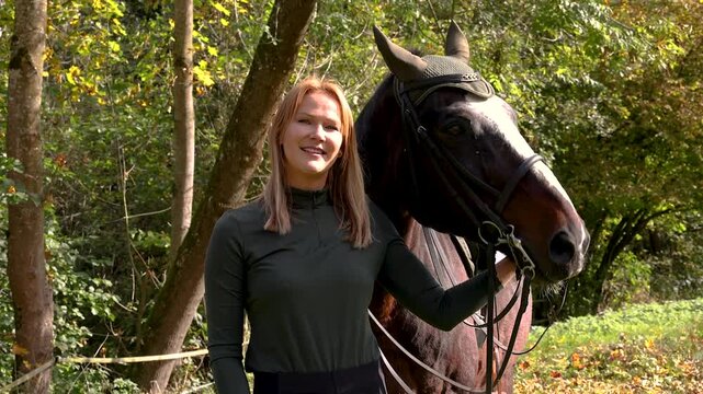 Close-up video portrait of a blonde woman with her brown warmblood horse, emotional connection outdoors