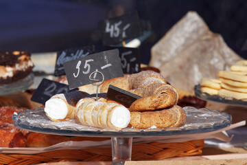 Glass stand with traditional Czech desserts at a farmers market stall in Prague, featuring kremrole and walnut rolls.