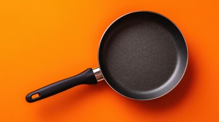 Top view of a non stick frying pan on orange background, kitchenware