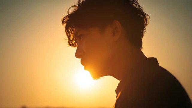 男性が朝日の中で俯く影