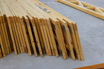 Piles of wooden roofing joins beams lined up at construction site for building work.
