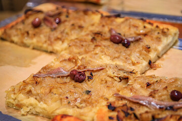 Sliced oissaladiere with anchovies, savory provencal tart with onions and olives at a restaurant in Old Town or Vieille Ville of Nice, South of France