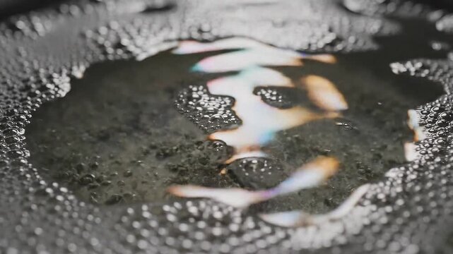 光にきらめく食器用水面に浮かぶ油膜の幻想的な輝き