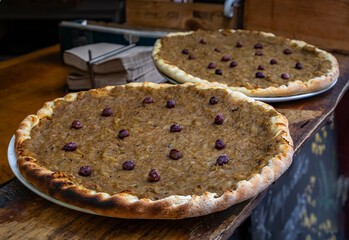 Pissaladiere, a savory provencal tart with onions, olives and herbs on display at a restaurant in Old Town or Vieille Ville of Nice, South of France