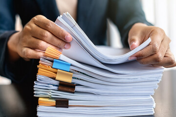 Hands sorting and organizing a large stack of business documents with colored clips