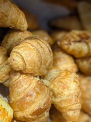 A close-up shot of a pile of golden-brown croissants, showcasing their flaky layers and inviting texture.