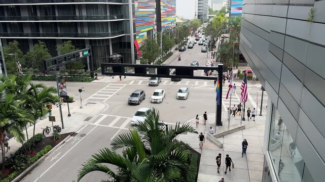 Miami, FL, USA, June 27, 2025: SLOW Car movement at the intersection of Brickell Plaza with S Miami Ave from the Brickell City Centre, Brickell Heights and SLS Lux rainbow stripped mural in background
