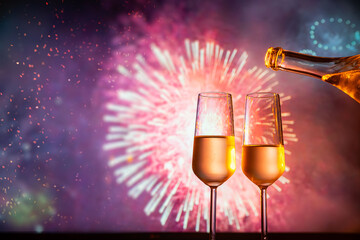 two glasses of champagne clink against the backdrop of New Year's fireworks