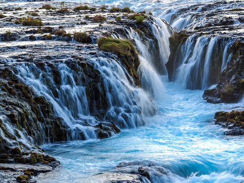 Multiple streams of vivid blue waterfalls flowing through rocky terrain in natural landscape