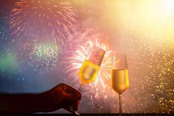 two glasses of champagne clink against the backdrop of New Year's fireworks
