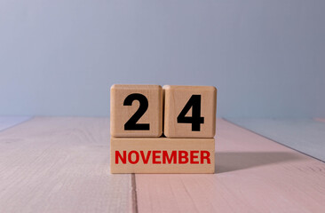 Wooden calendar organizer with date november 24 and decorative plant on table.
