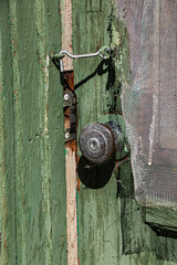 An old green painted door is latched closed with a hook.