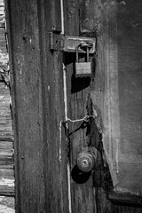 A series of latches and locks on a weathered and worn door.