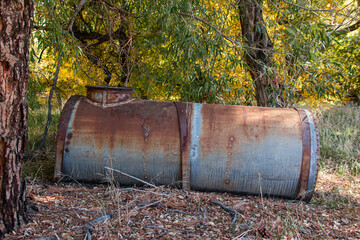 An old galvanized metal tank used for water storage near an abandoned residence in the woods.