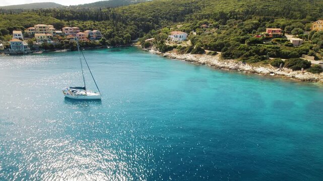 Sailboat anchored near coastal village Fiskardo and green forest in Kefalonia