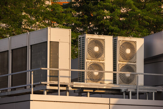 Industrial air conditioning and ventilation units installed on a rooftop platform, illuminated by warm evening sunlight