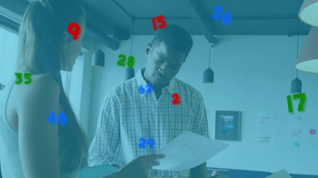 Colleague starting office review by pointing at document, partner leaning nodding confirming layout