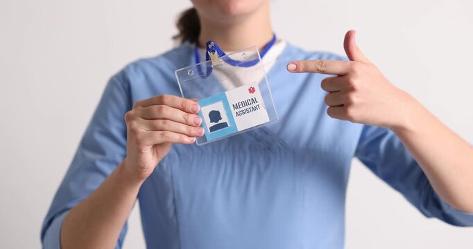 Medical assistant showing her badge on light background, closeup. Camera moving up