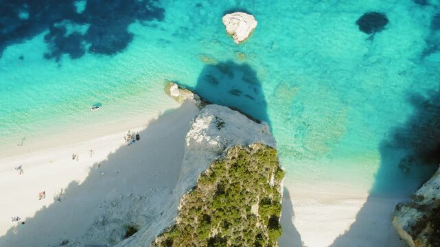 Overhead view of white sand beach and turquoise sea with people sunbathing in Kefalonia, Greece